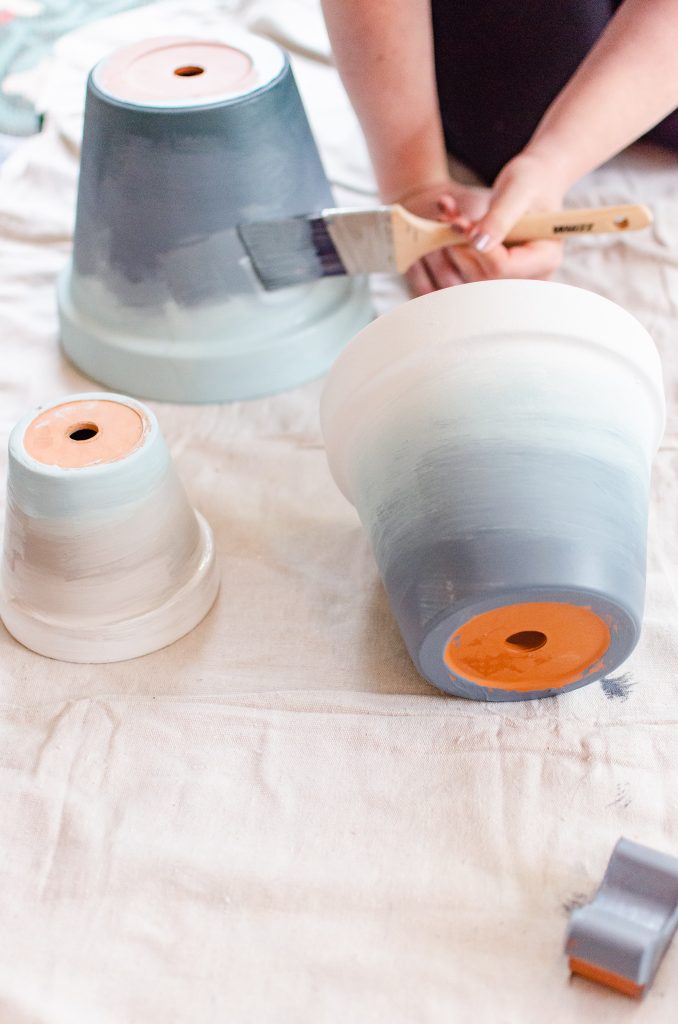 Ombre terracotta pots being painted with a paintbrush