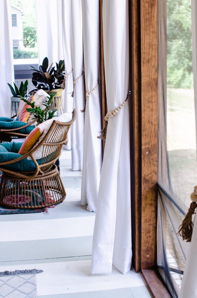 White curtains with wooded beaded tassel tie backs on back porch patio | HauteHouseLove.com