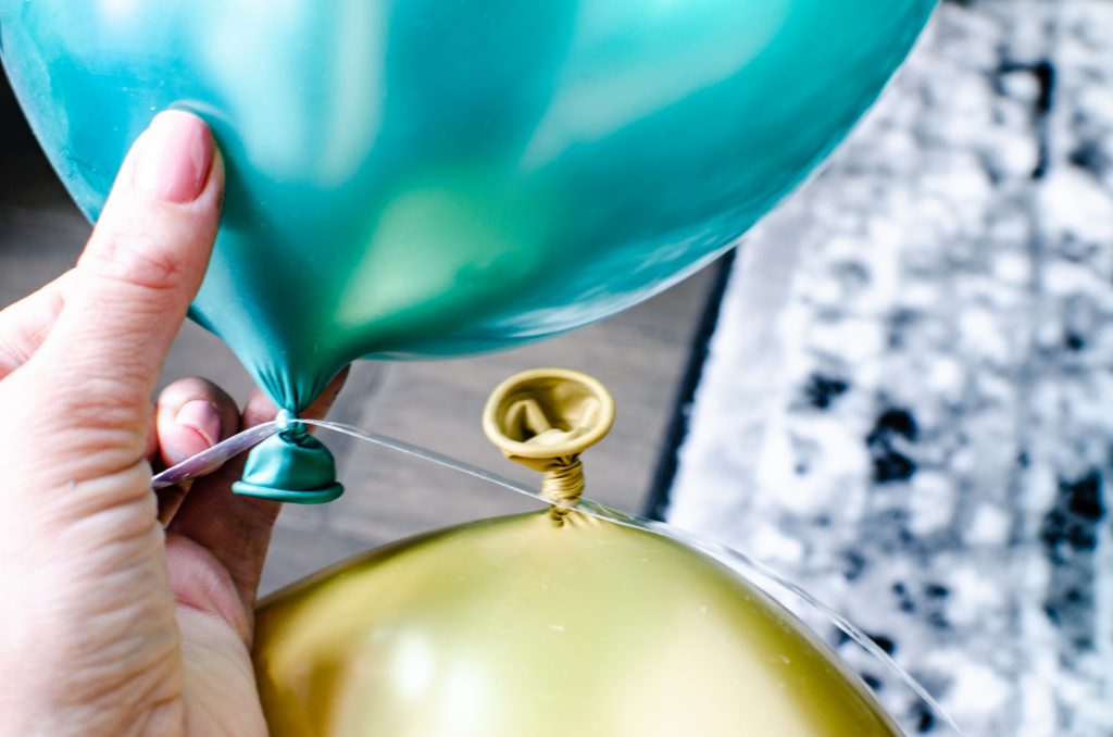 Two balloons on a plastic strip for a DIY balloon garland | HauteHouseLove.com