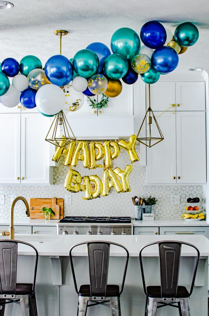 blue, green and gold birthday balloon garland in a white farmhouse kitchen