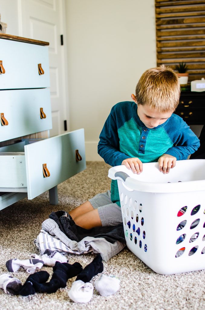 Child putting away clothes in organized drawers