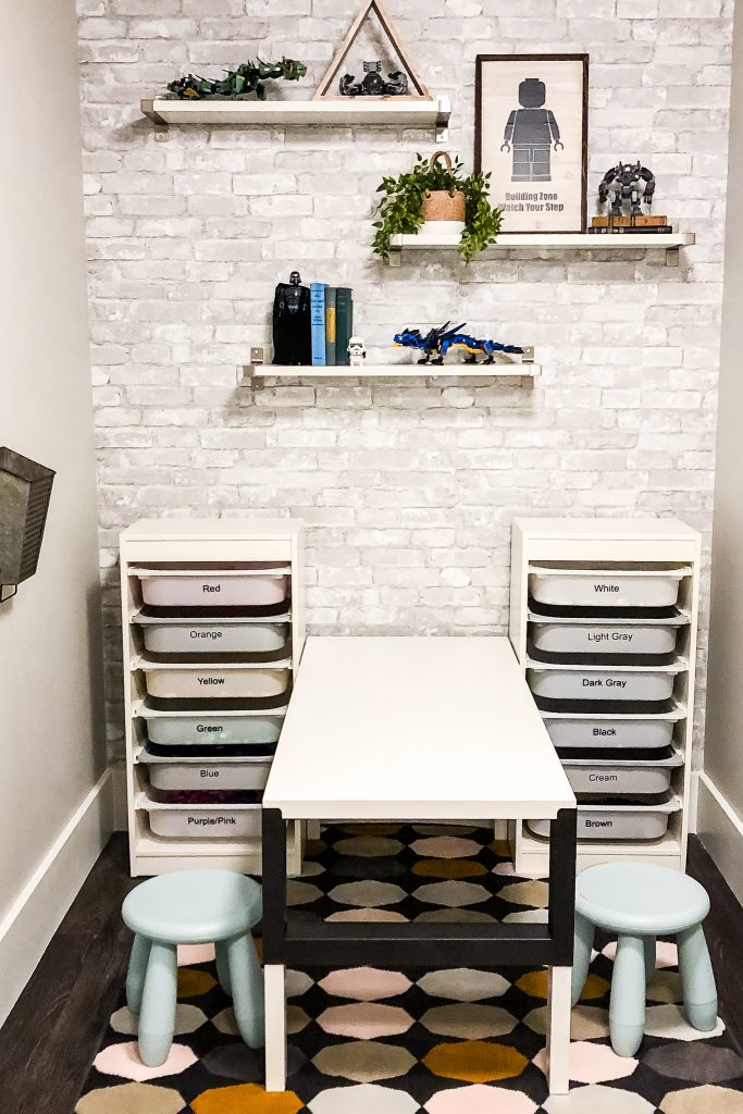 Lego storage in a decorated lego room with brick wallpaper accent wall