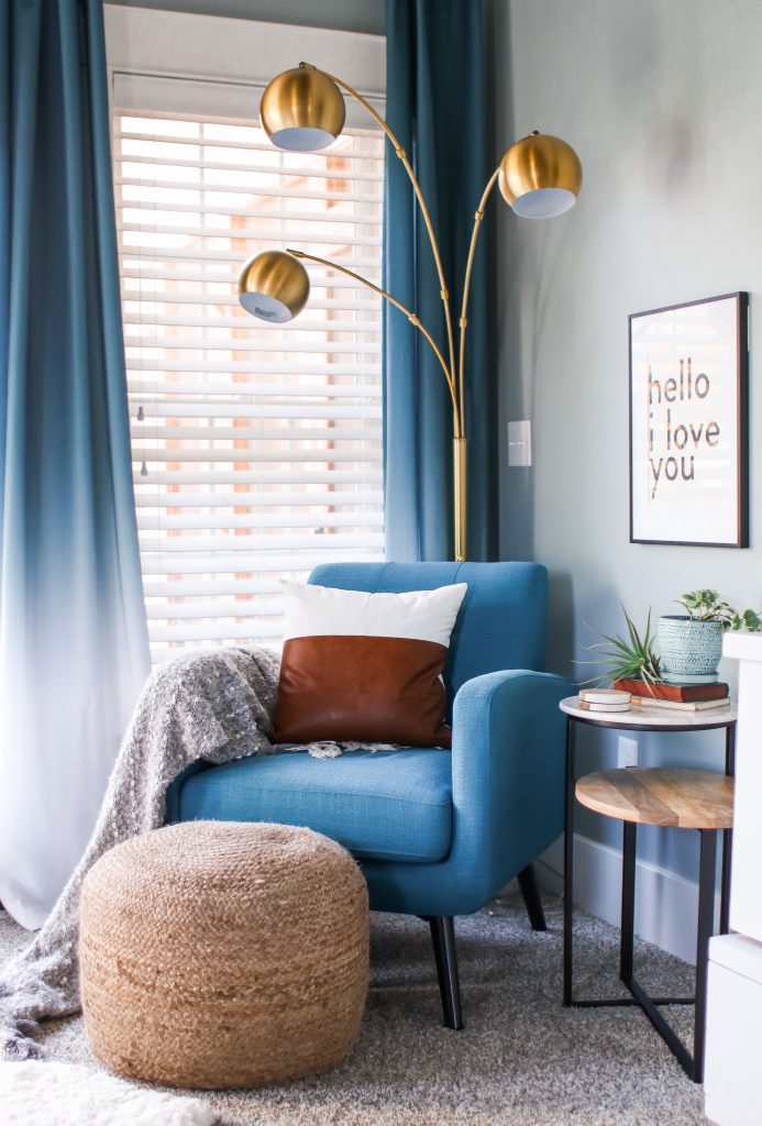 Master bedroom reading nook with blue chair and modern accents.