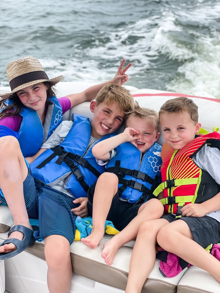 Four kids in life jackets on a boat in water, family vacation | Random Thoughts from The Weekender on HauteHouseLove.com