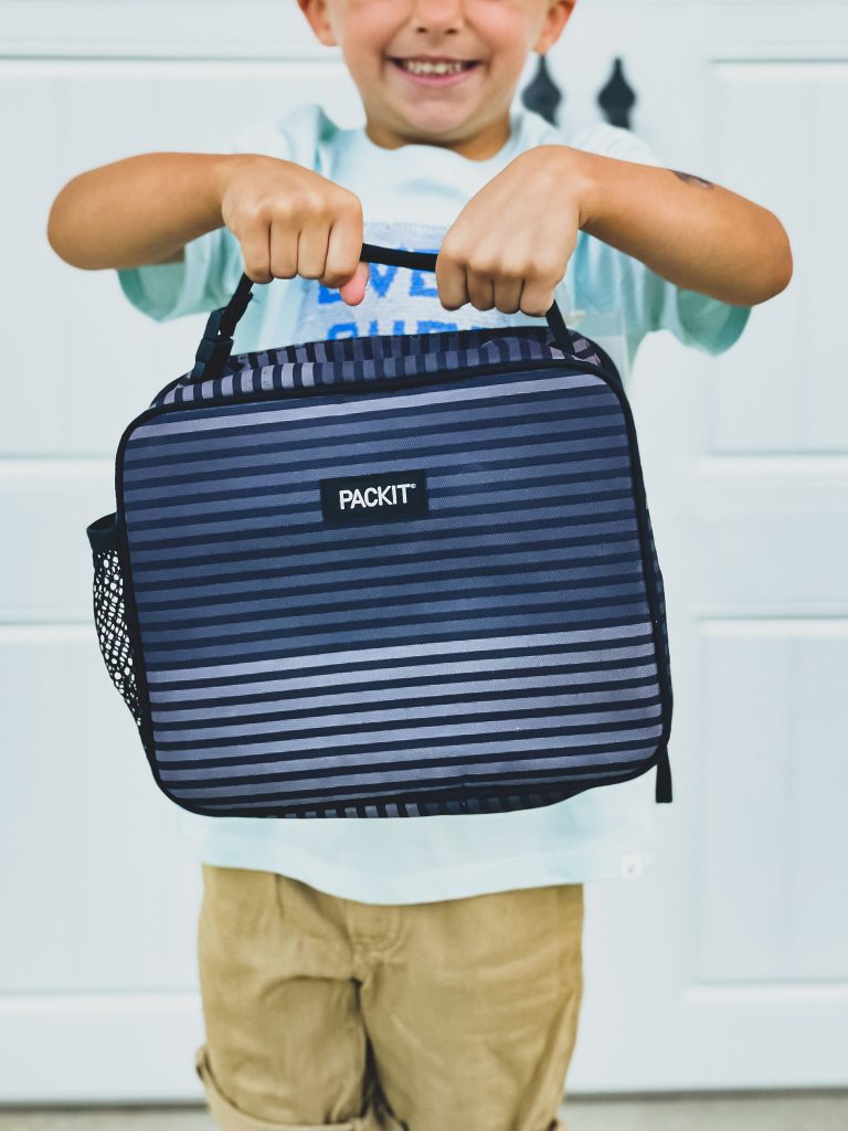 Young boy holding blue striped lunchbox | HauteHouseLove.com