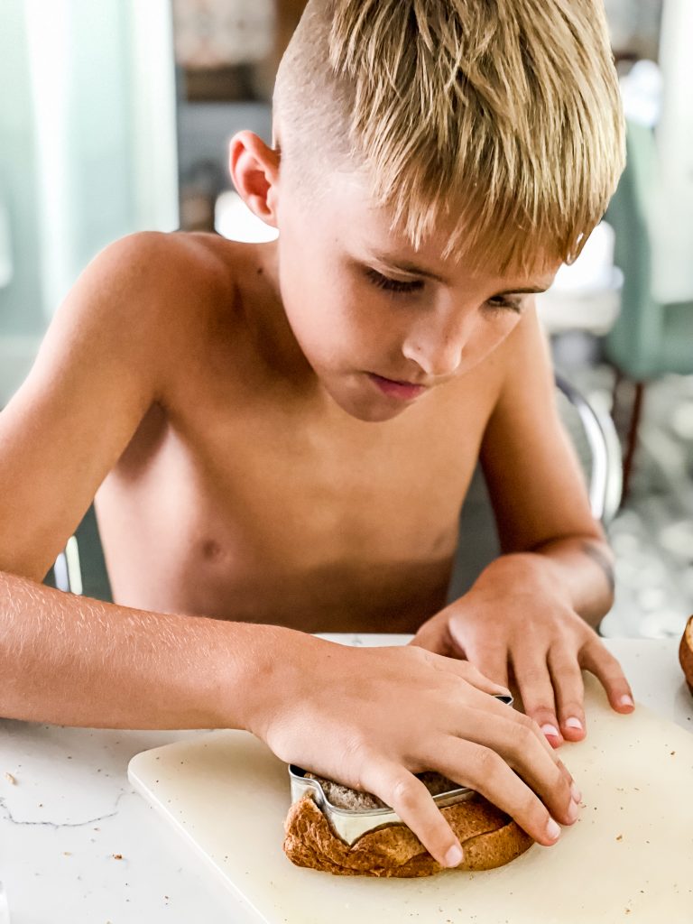 Young boy using cookie cutter on his sandwich bread for school lunchbox | HauteHouseLove.com