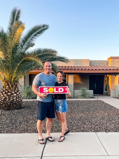 Husband and Wife holding SOLD sign in front of Arizona home