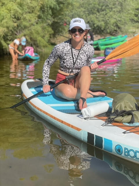 Woman on a paddleboard in a river, holding an oar