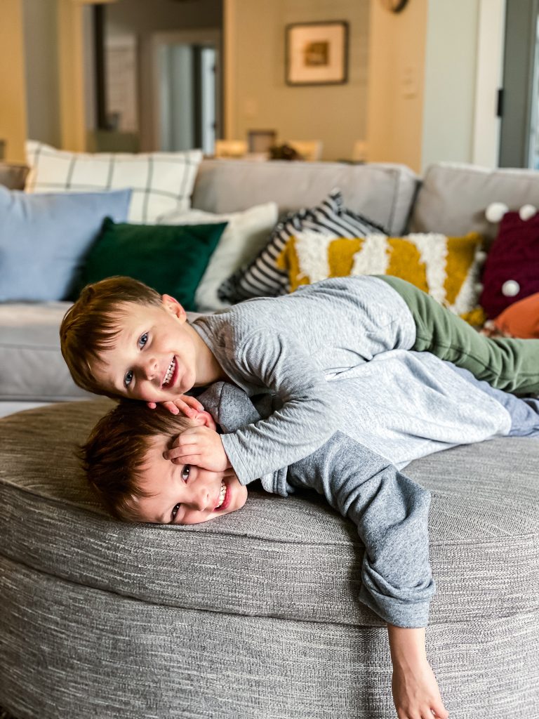 Young boys smiling and wrestling on the couch | Modern Boho Home Decor Style on Haute House Love