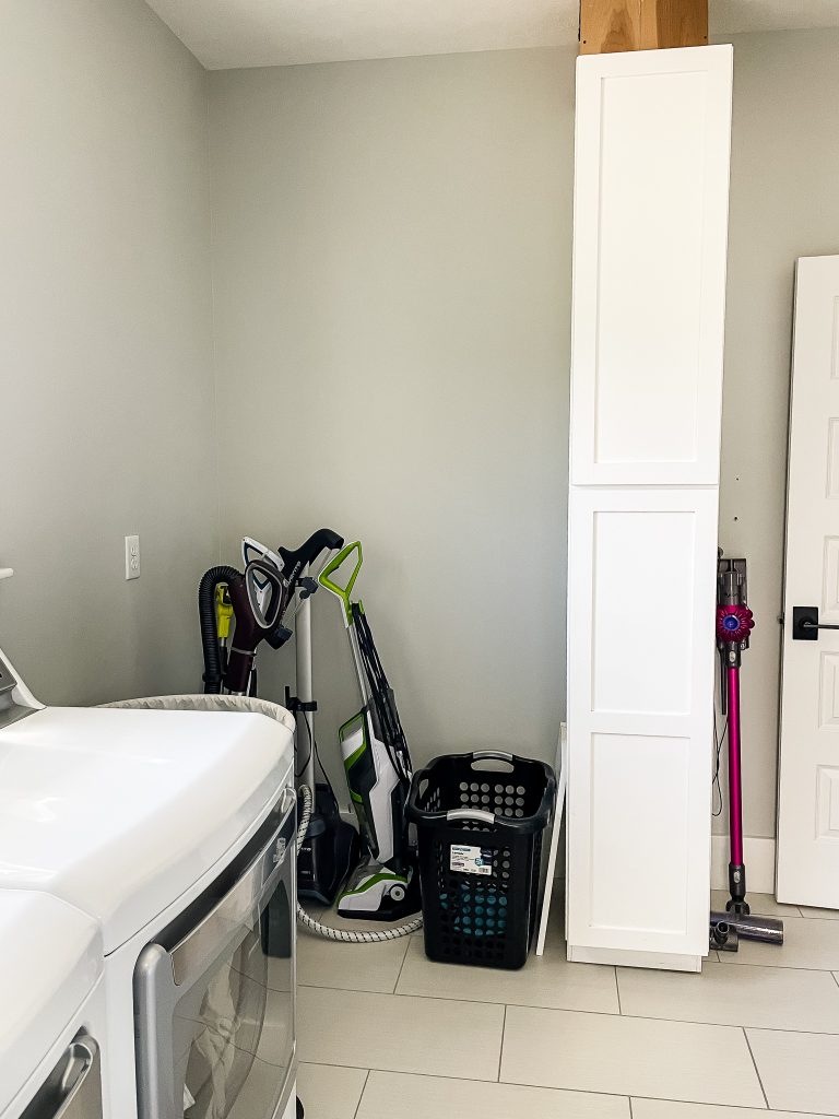 corner of a laundry room with a laundry chute and missing cabinets