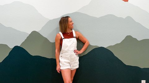 woman standing in front of a completed DIY Mountain Mural