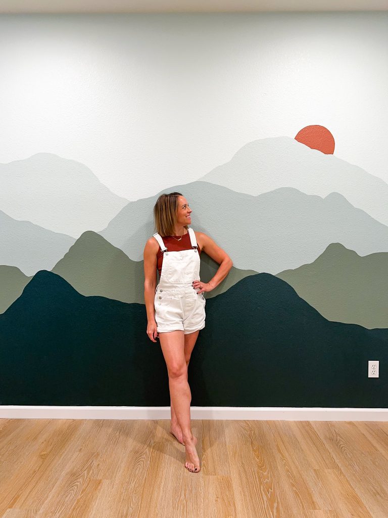 artist in front of a DIY Mountain Mural