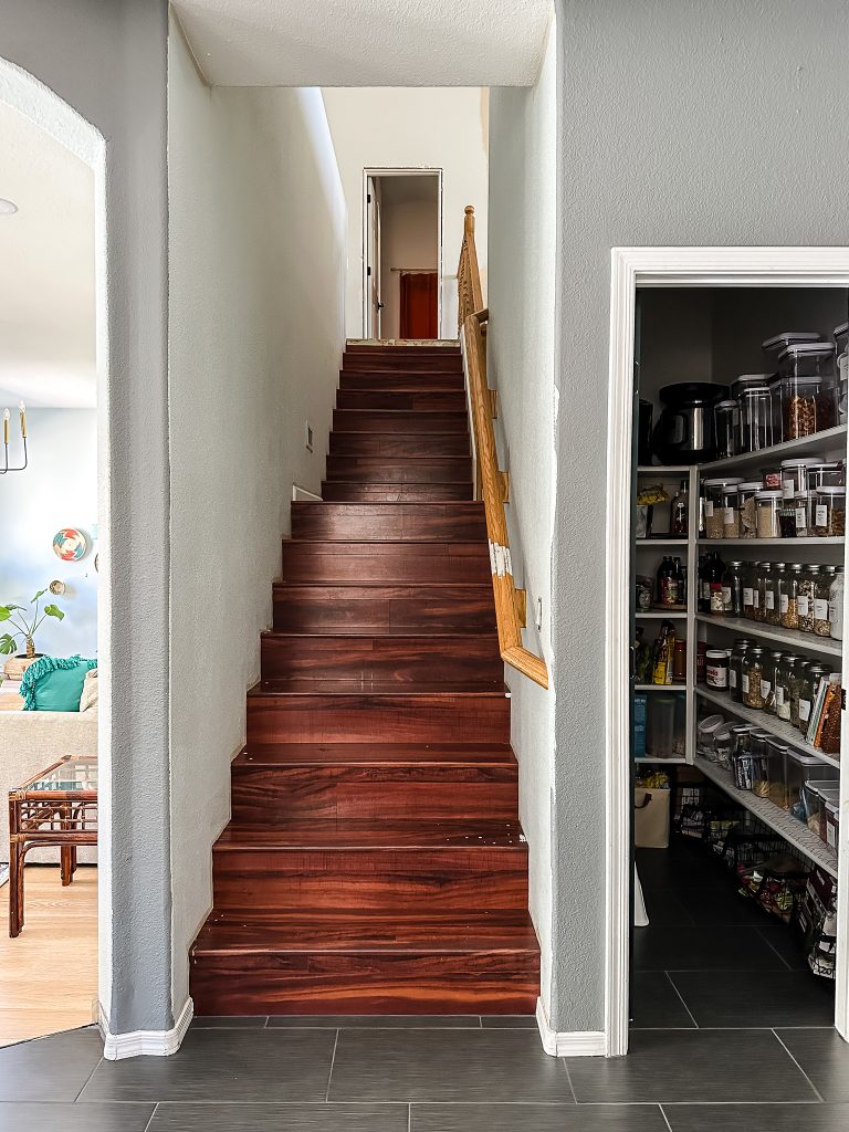 Dated staircase with cherry laminate floors next to a walk in pantry